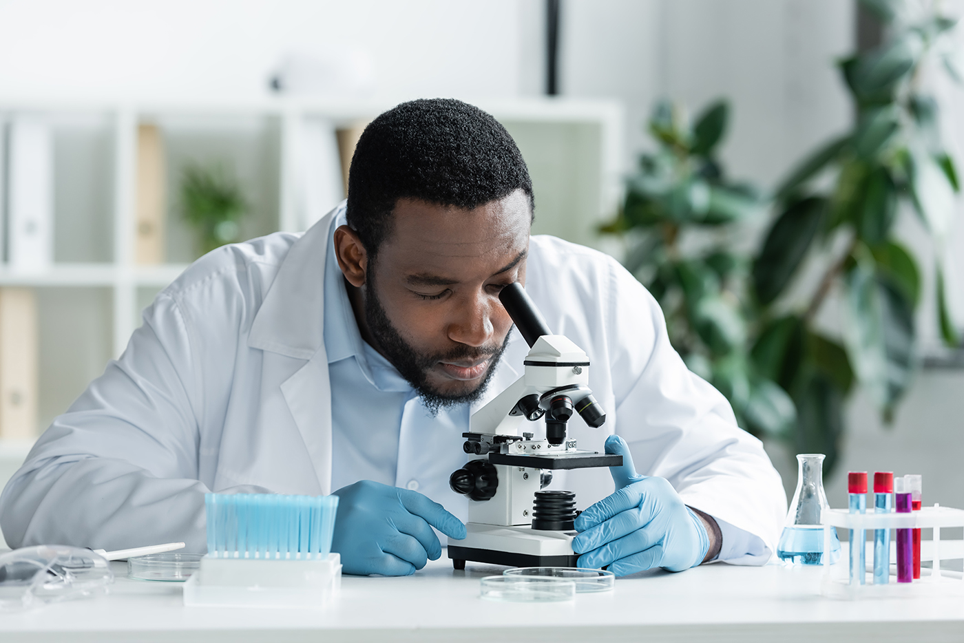 Scientist in latex gloves working with stethoscope, test tube and flask.